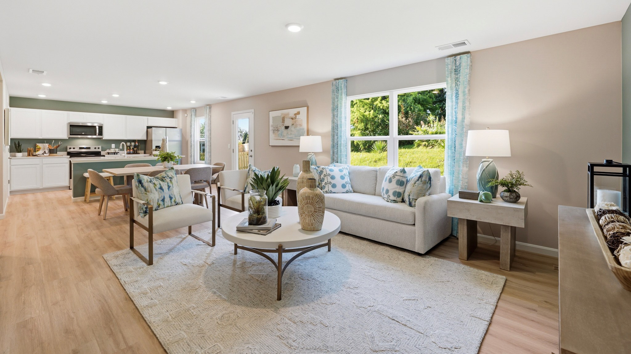 Living room with double window, couch, two accent chairs, coffee table, rug, and LVP flooring.