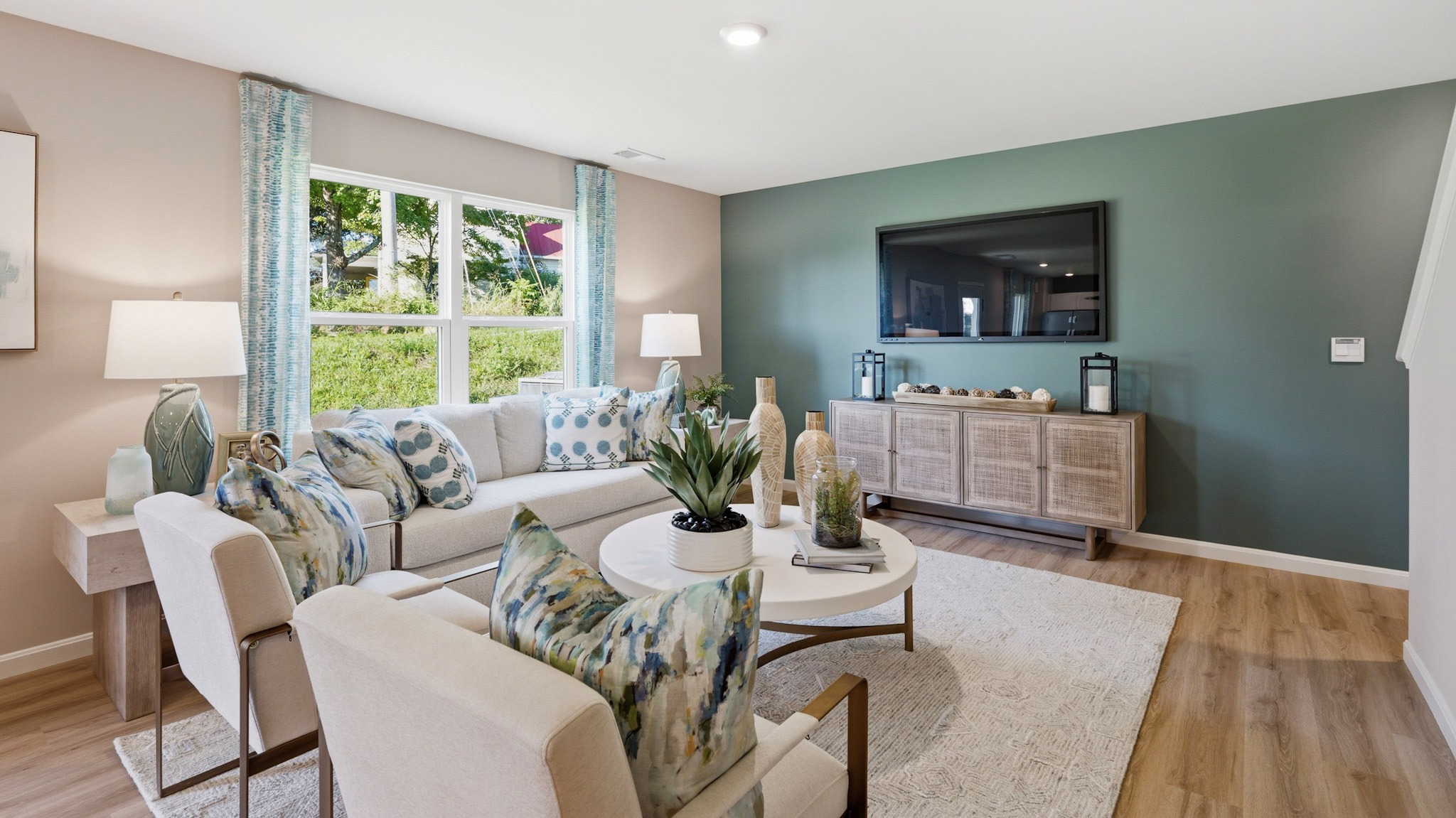 Living room with double window, couch, two accent chairs, and wall-mount tv.
