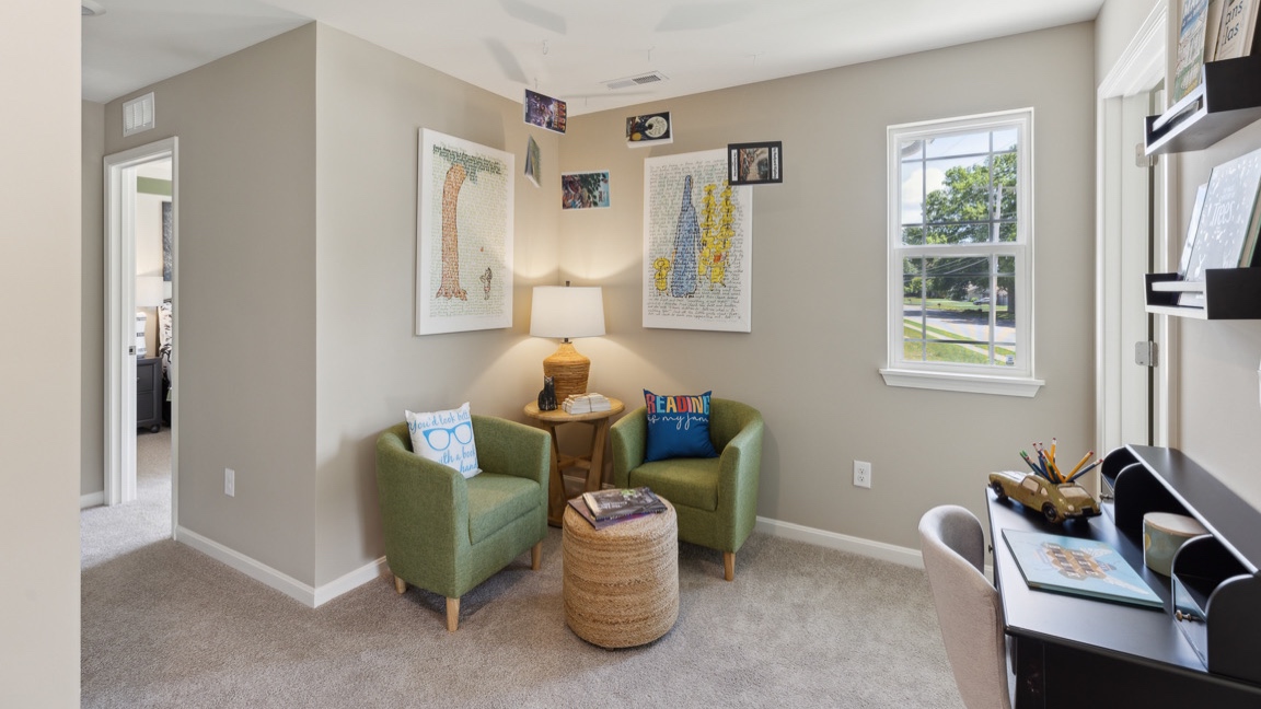 second floor loft with window, two accent chairs, and two accent tables