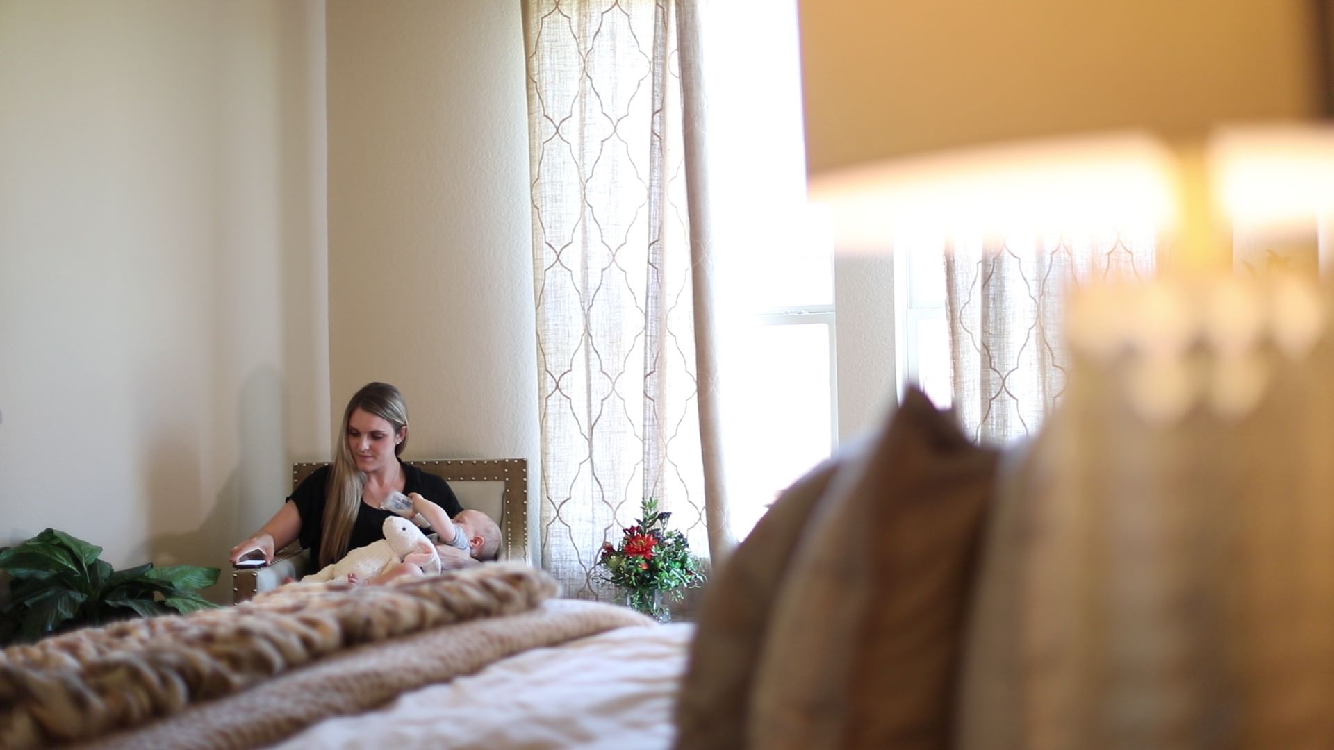 Mother sitting in an accent chair with baby in the primary bedroom