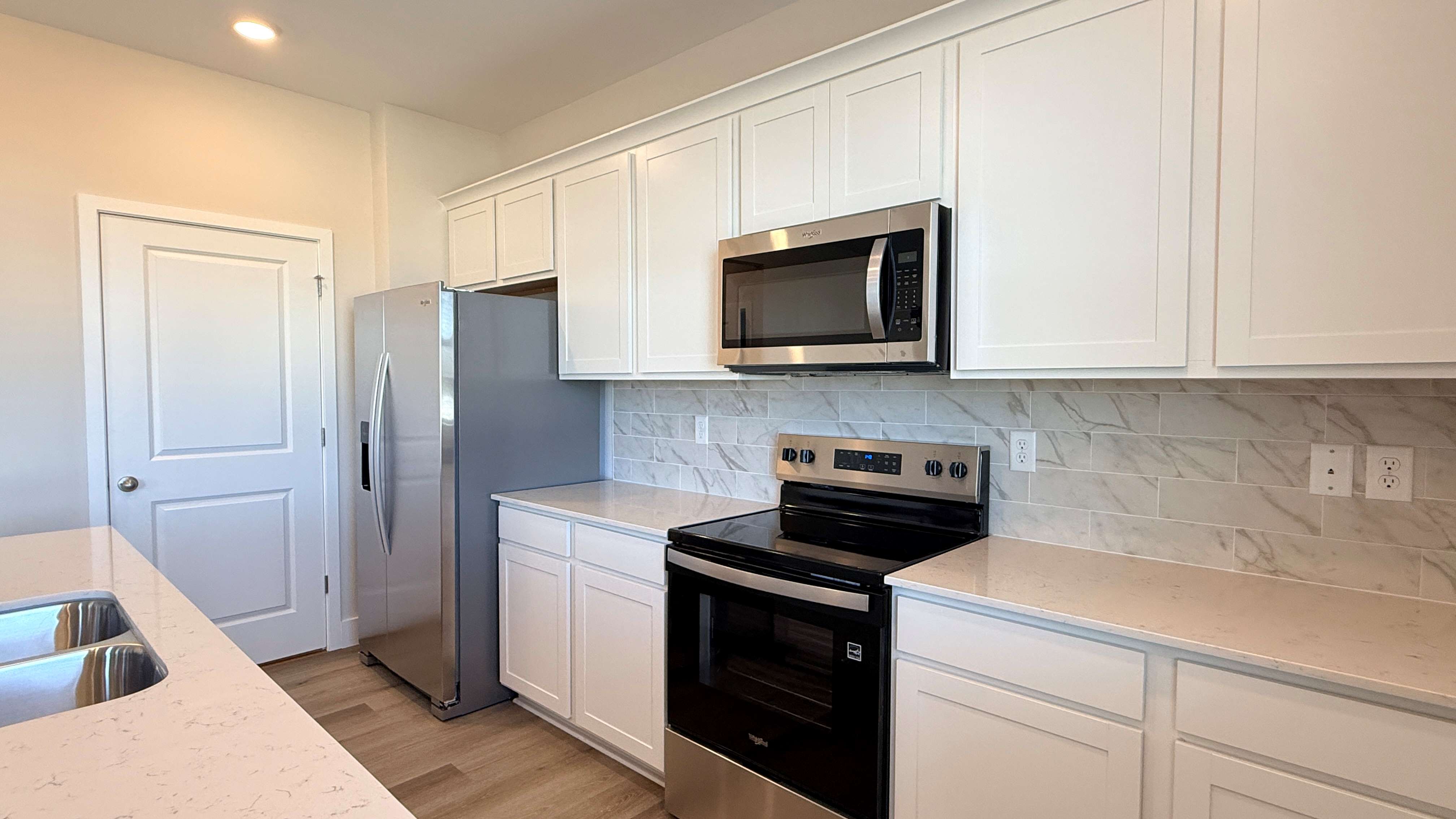 Kitchen with stainless steel appliances and white cabinets.