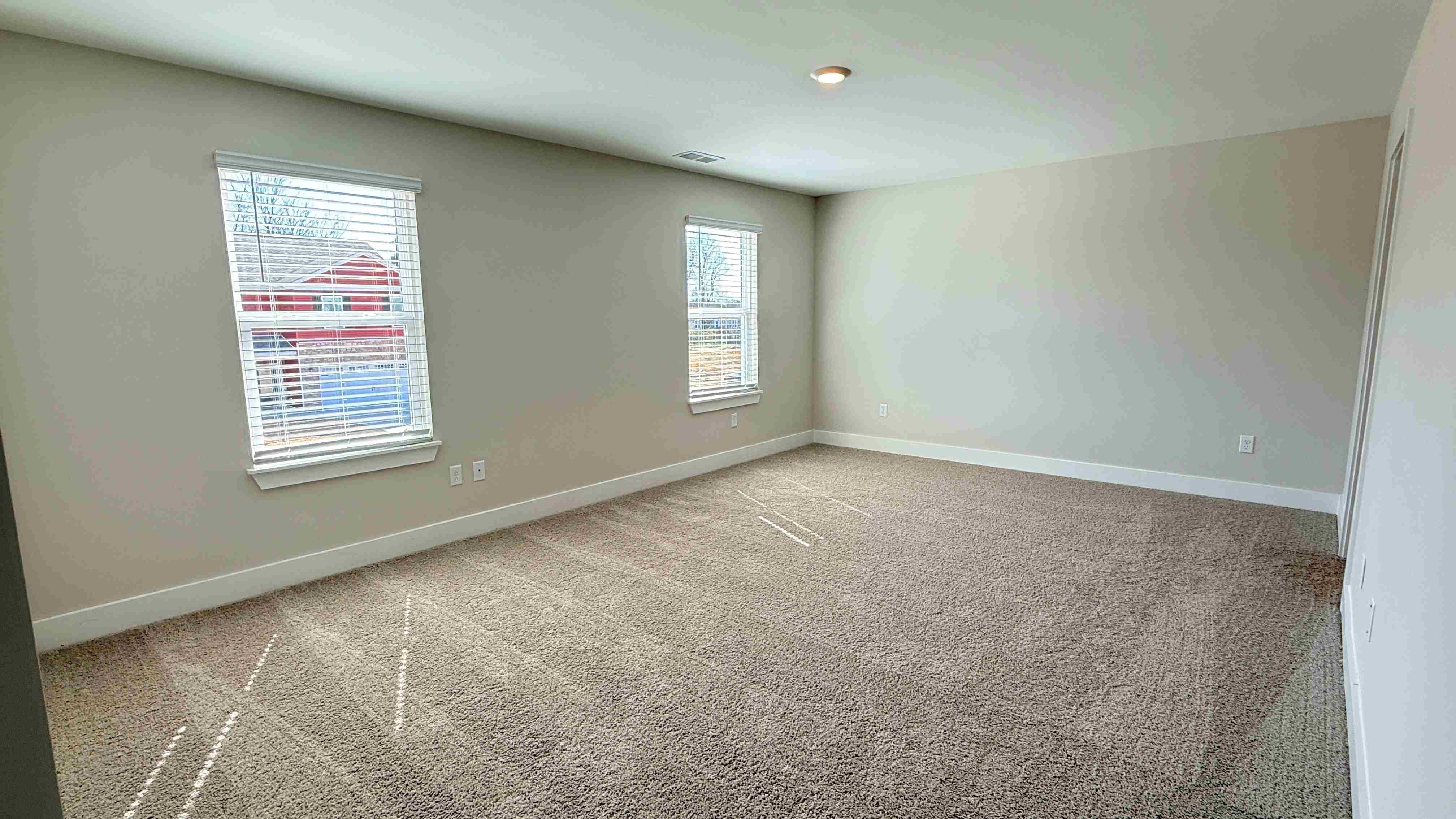 Upstairs primary bedroom with two single windows and carpet.