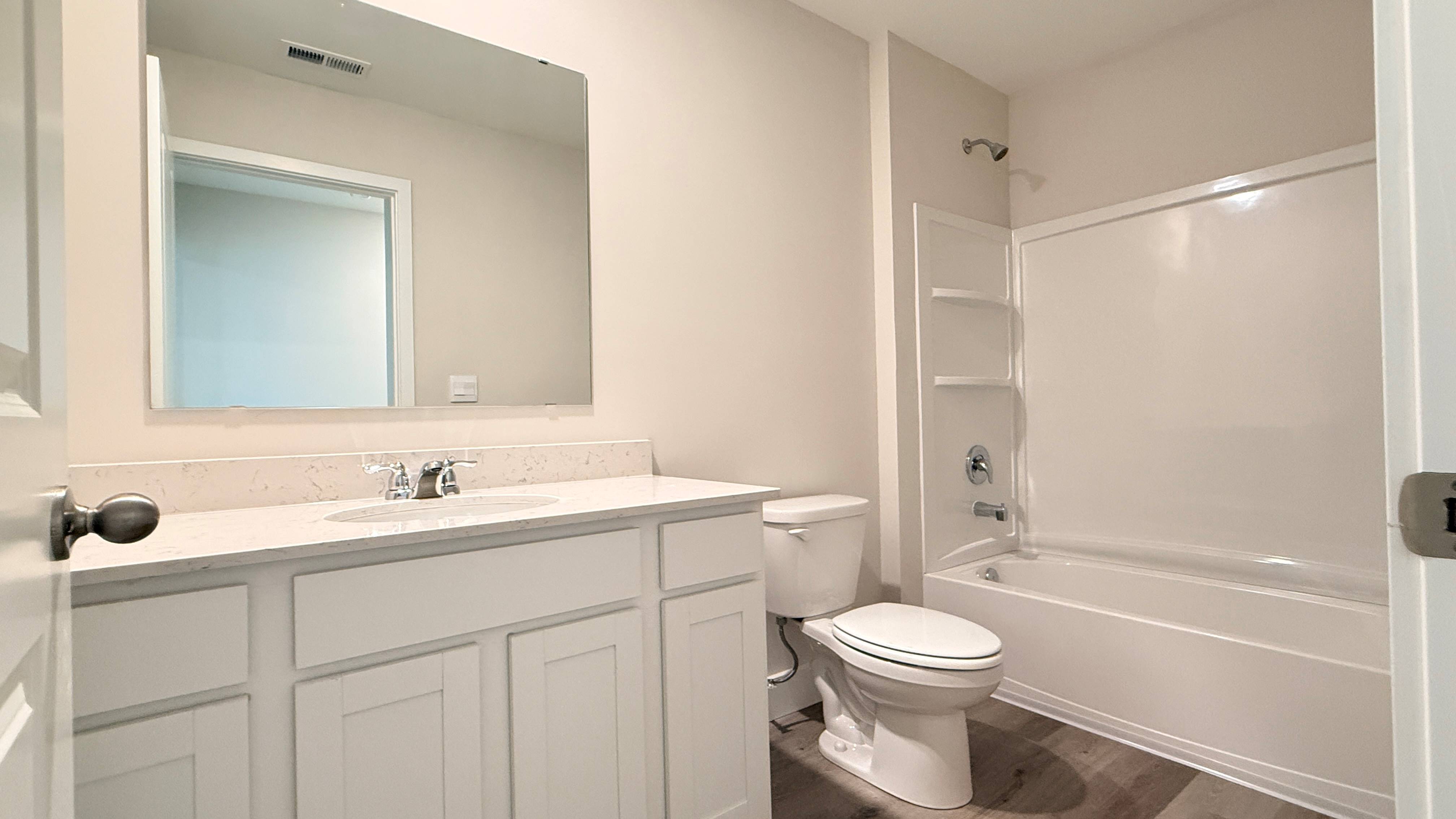 Upstairs shared bathroom with vanity, commode, and shower/tub combo.