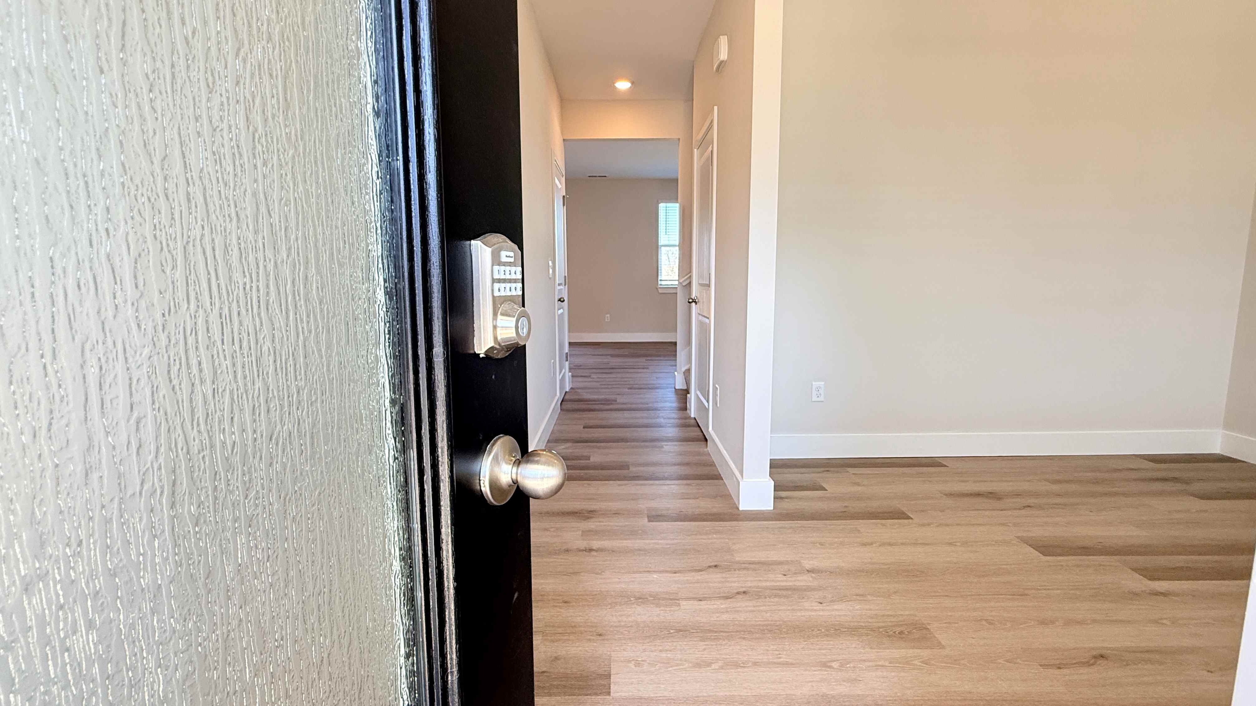View of front door opening into the foyer with a keyless entry pad.