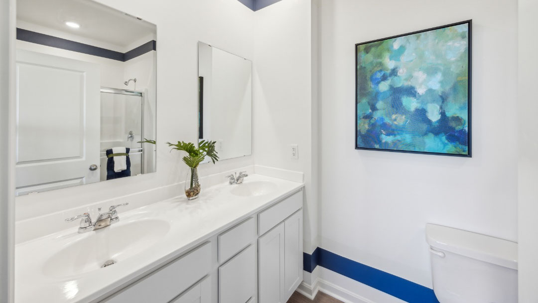 bathroom featuring dual sinks, white cabinetry and a mirror above each sink