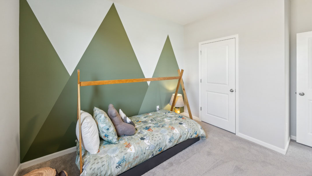 bedroom featuring green triangle accent wall, small bed, and woodsy decor