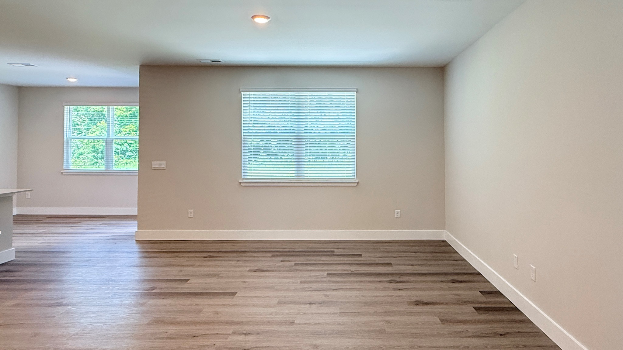 Living room with luxury vinyl plank flooring and a double window overlooking the backyard.