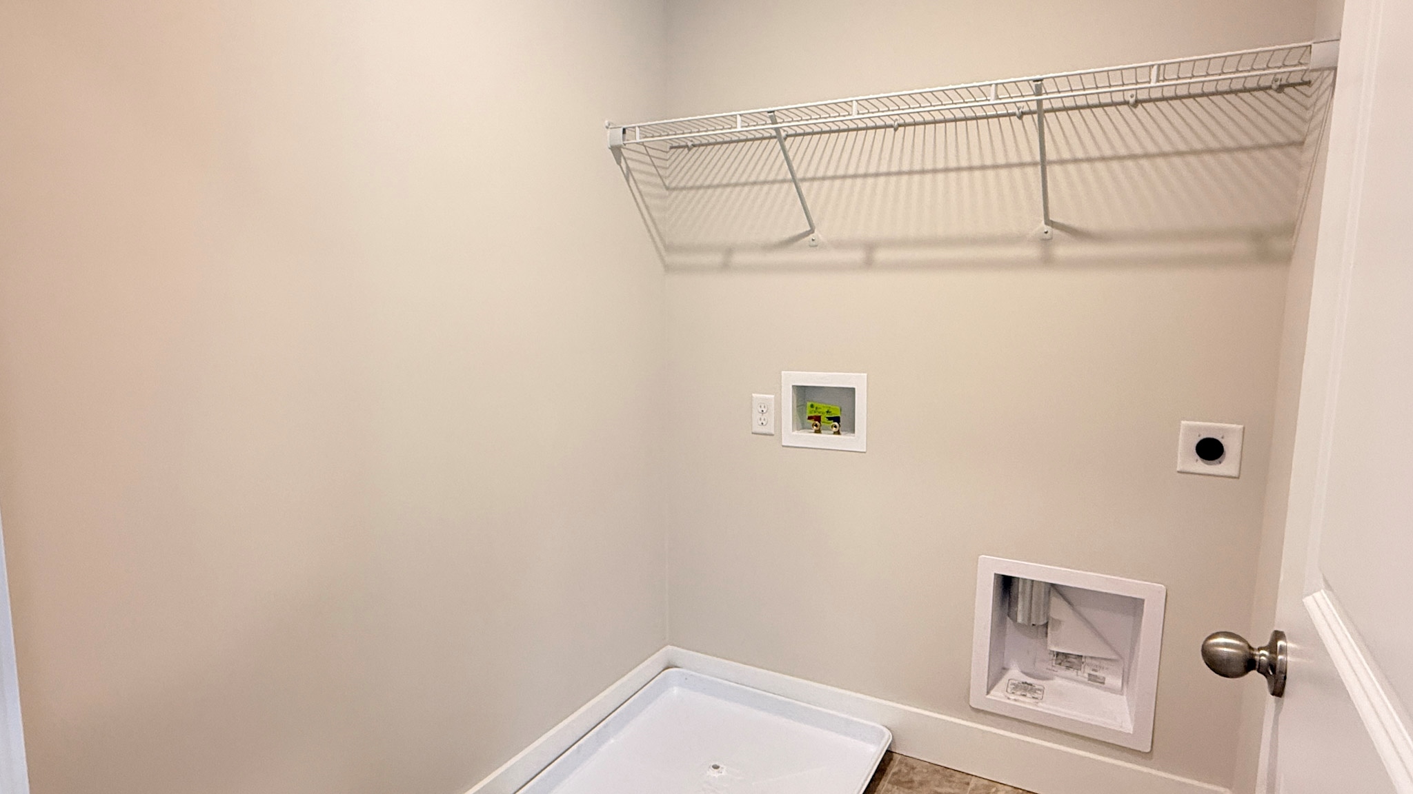 Second floor laundry room with washer pan and wire shelf above the washer/dryer locations.