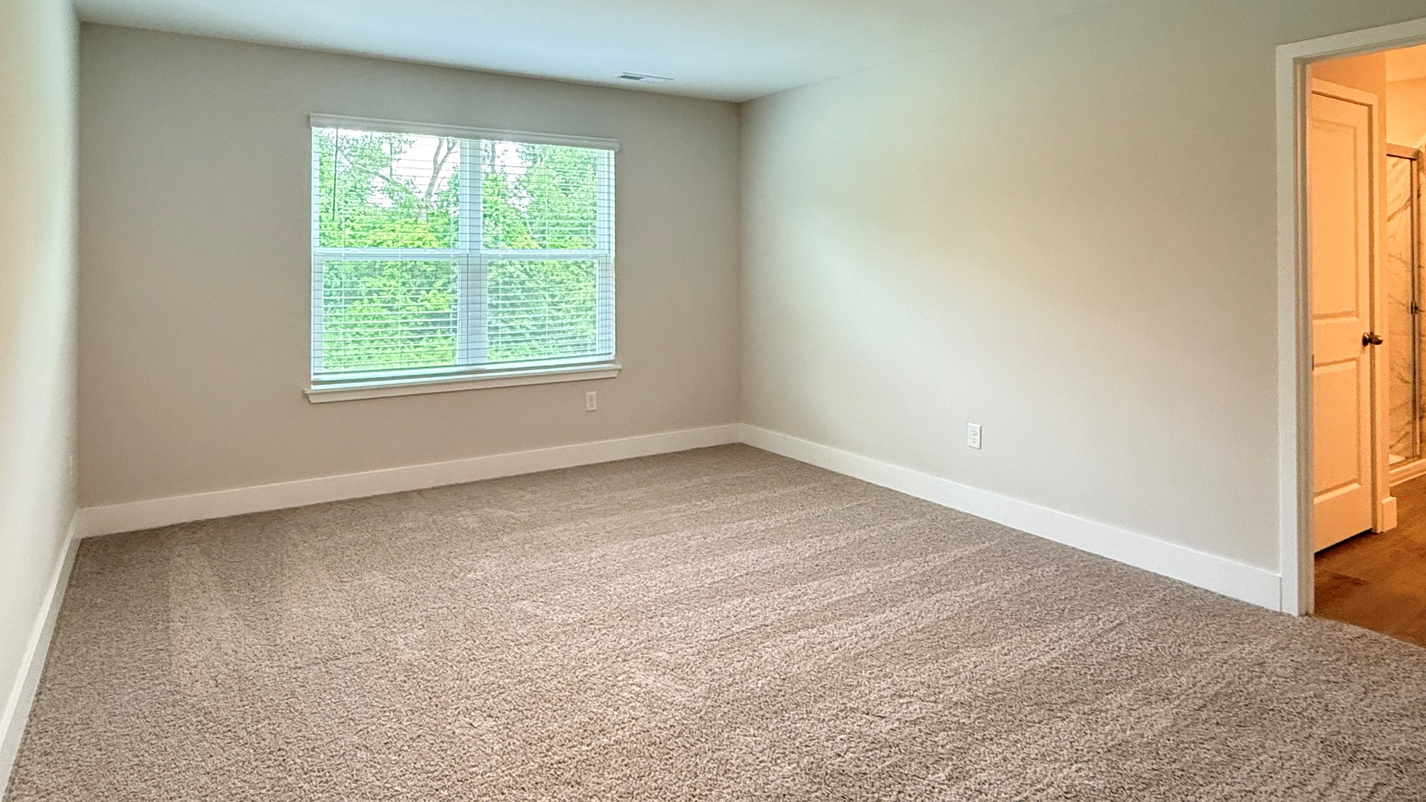 Second floor primary bedroom with a double window and carpet.