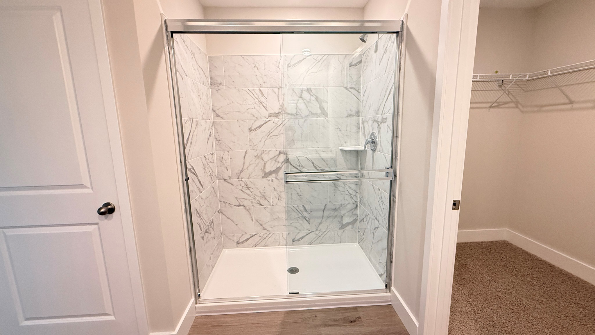 Primary tiled shower with a sliding glass door.