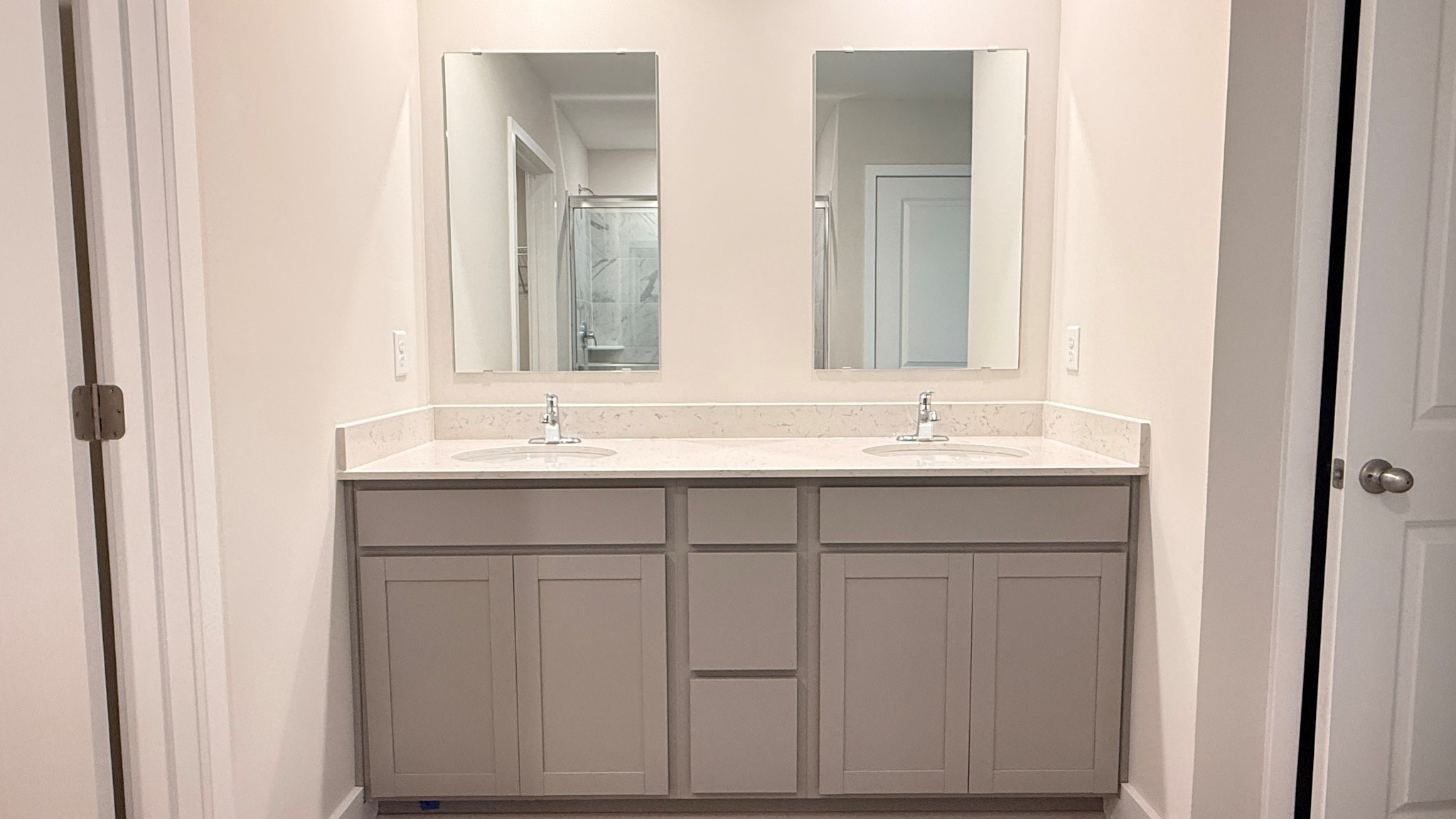 Double bowl vanity with gray cabinets and quartz countertops in the primary bathroom.