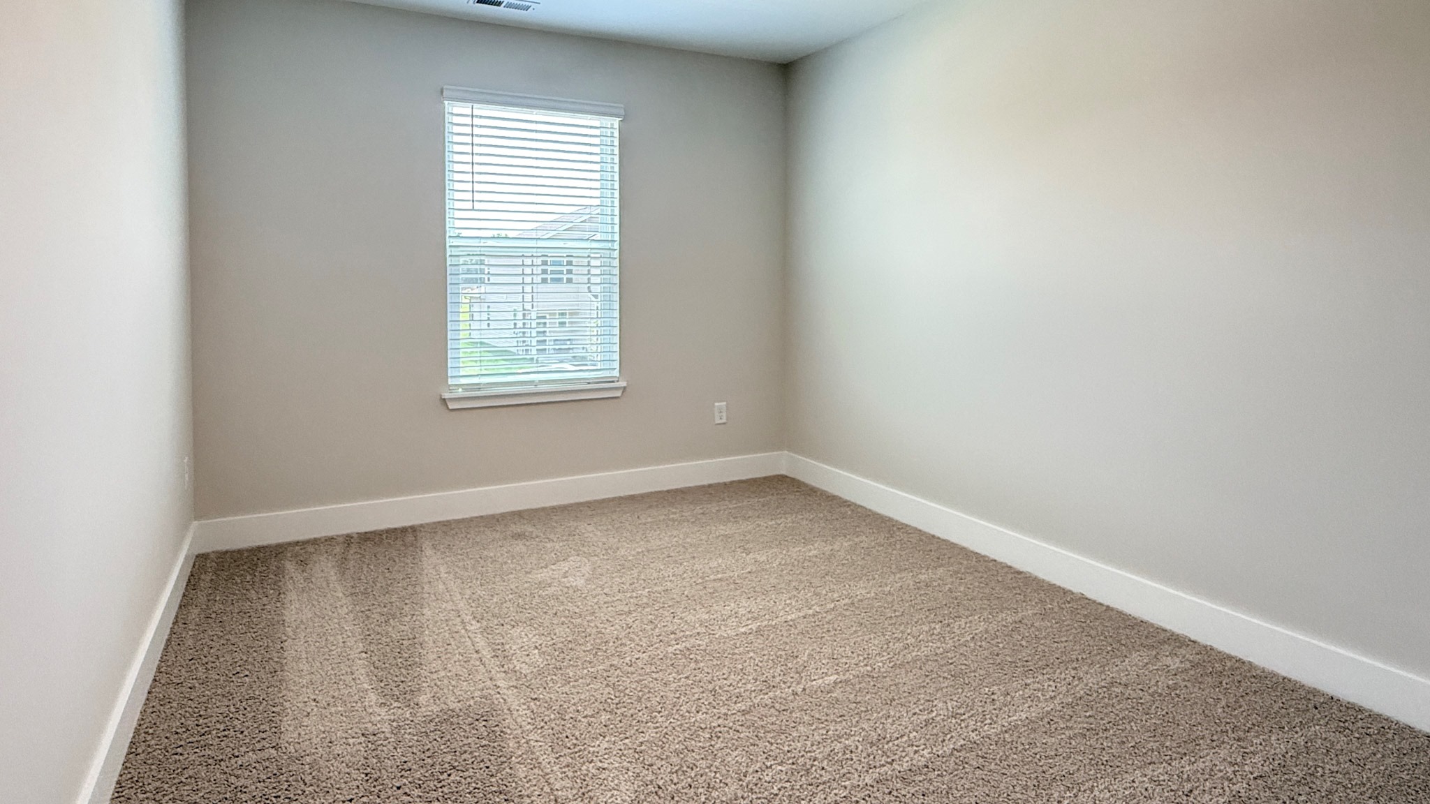 Spare bedroom with carpet and single window.