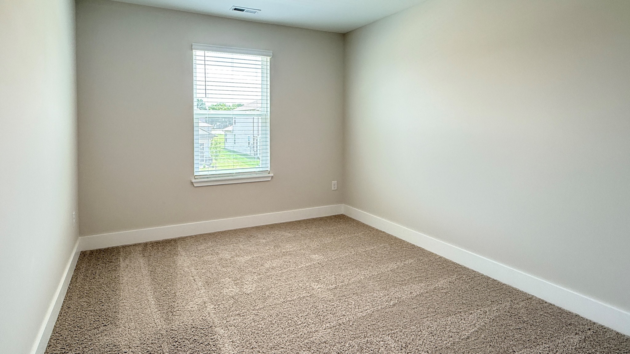 Spare bedroom with single window and carpet.