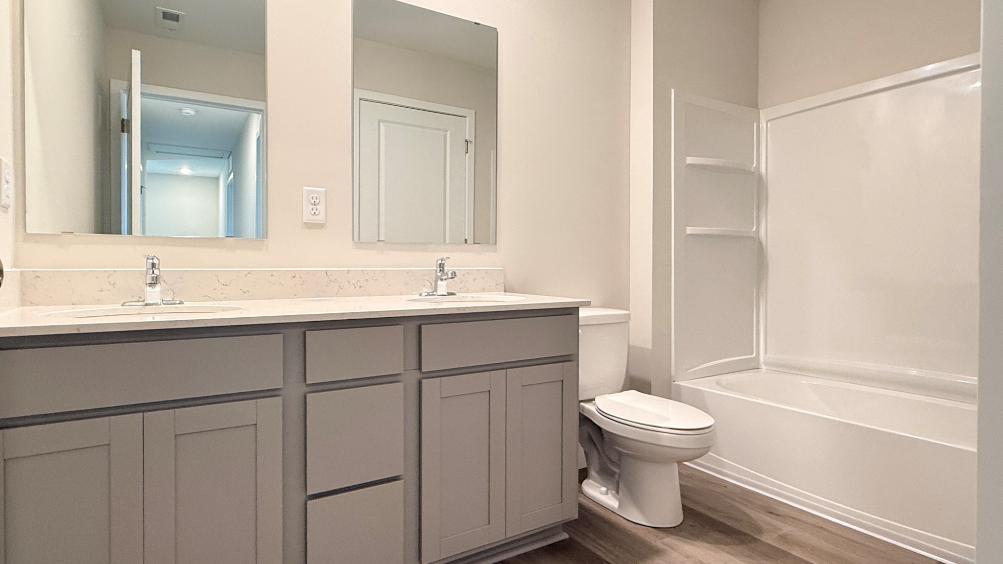 Second floor hall bathroom with a double bowl vanity, quartz countertop, white commode, and a white shower/tub combo.