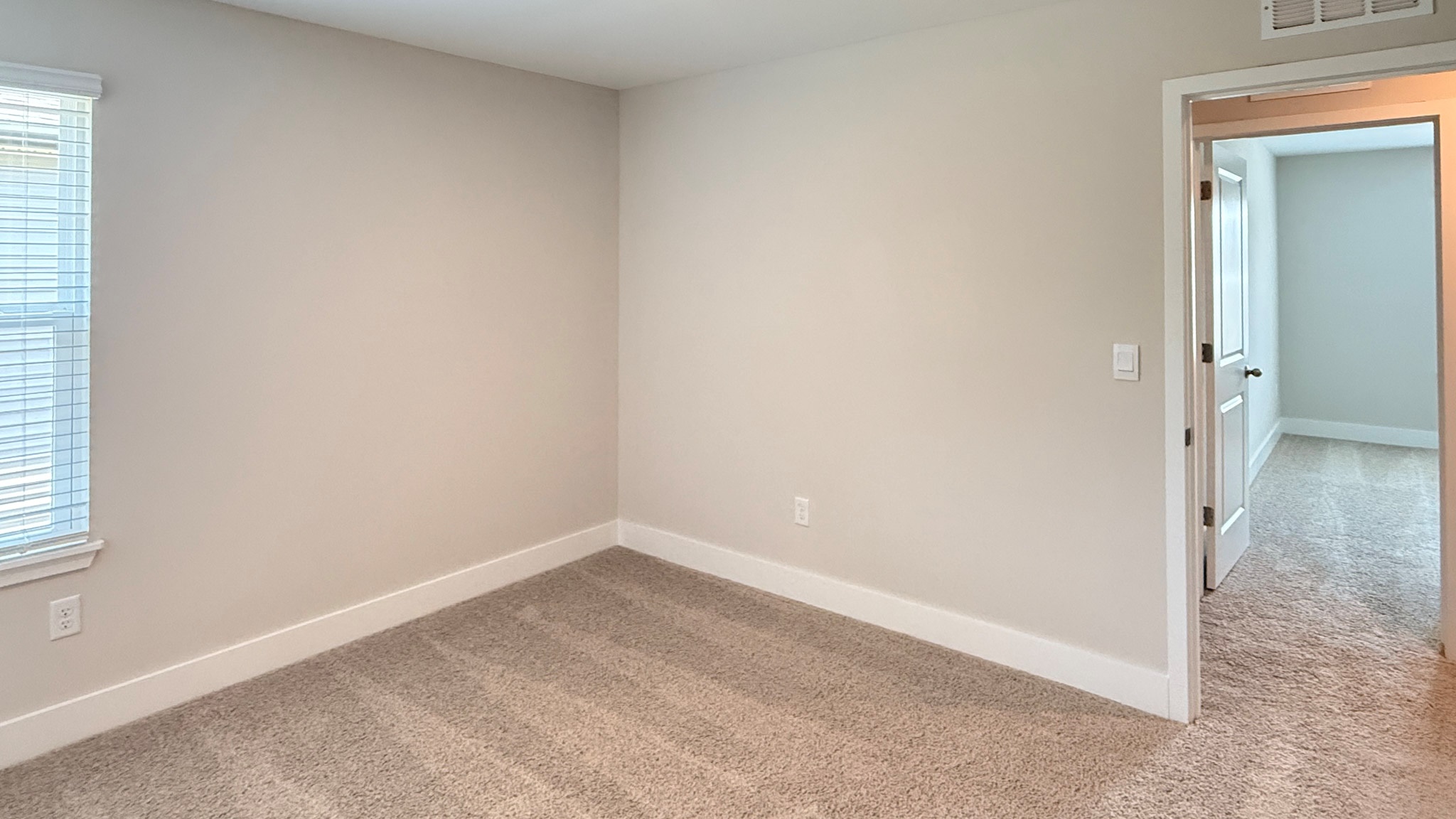 Spare bedroom with a single window, carpet, and bedroom entry door.