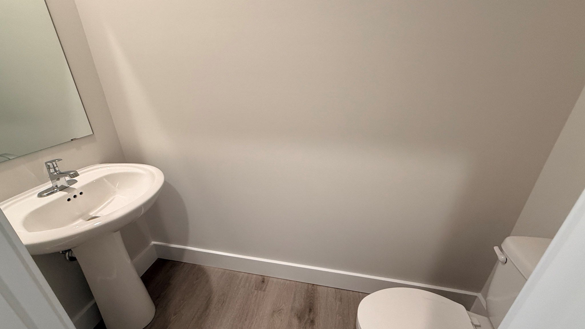 First floor half bathroom with a pedestal sink and a white commode.