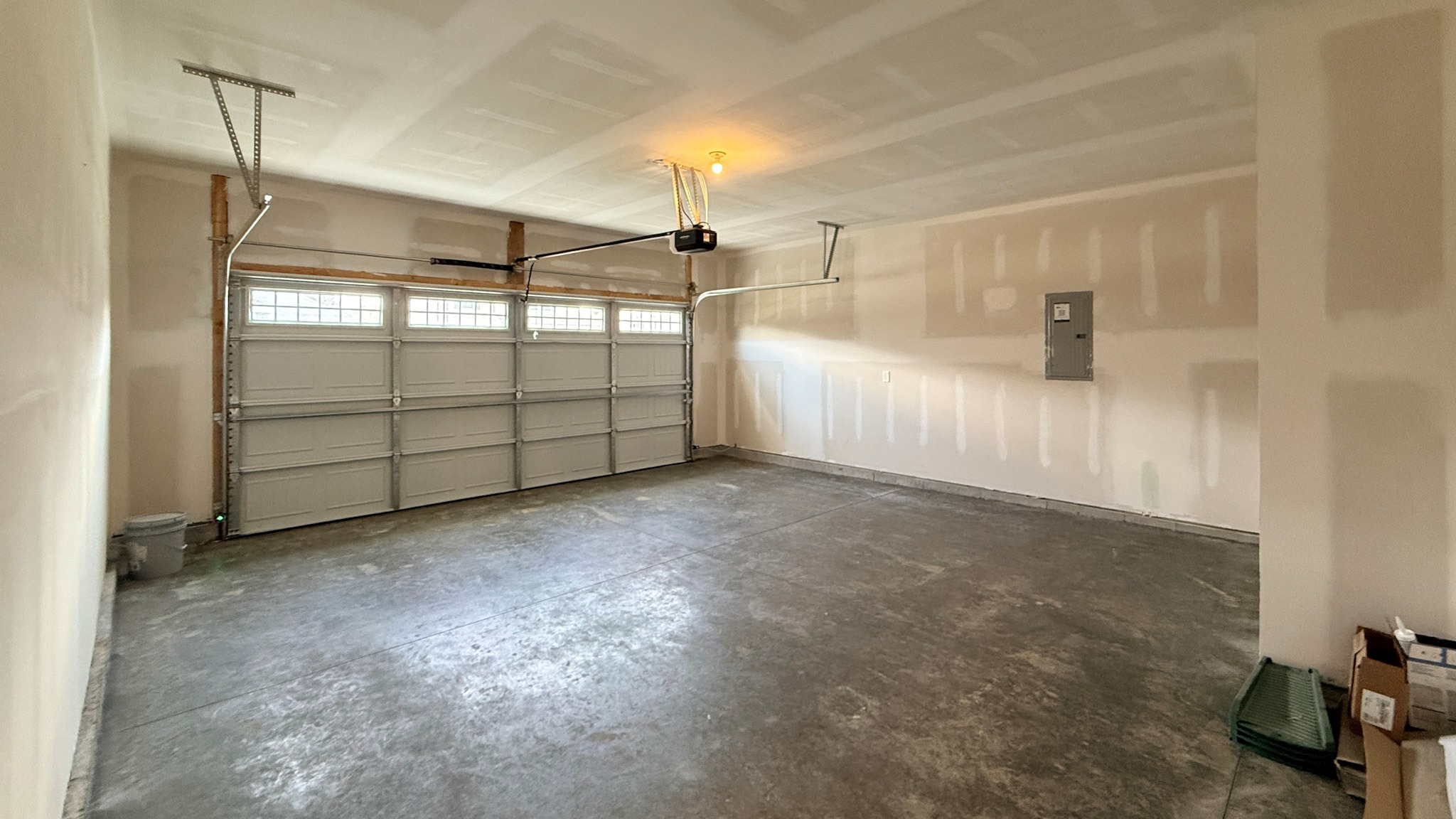 Inside of 2-car attached garage that is fully drywalled and with an automatic garage door opener.