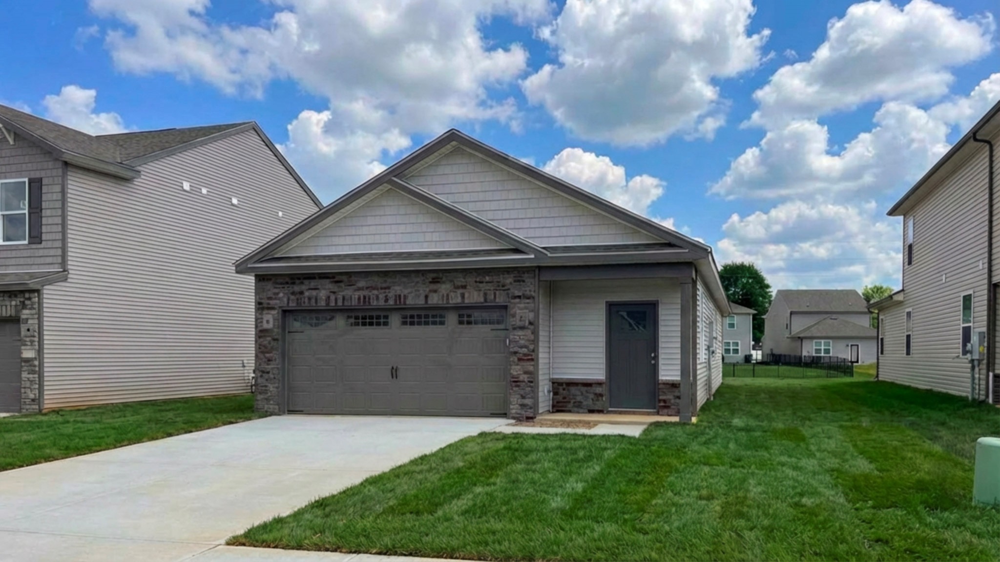 Downing floorplan with covered front porch and 2-car attached garage. Stone accents on the front of the house.