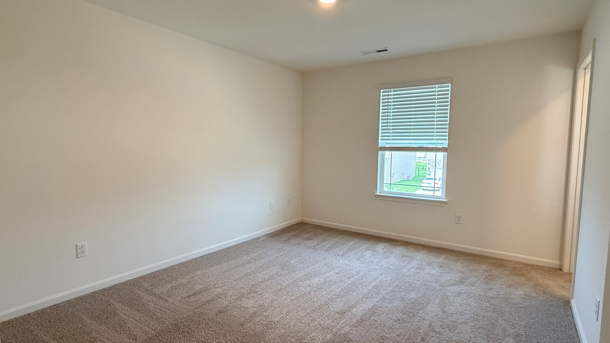 Second floor primary bedroom with window, carpet, walk-in closet, and ensuite bathroom.