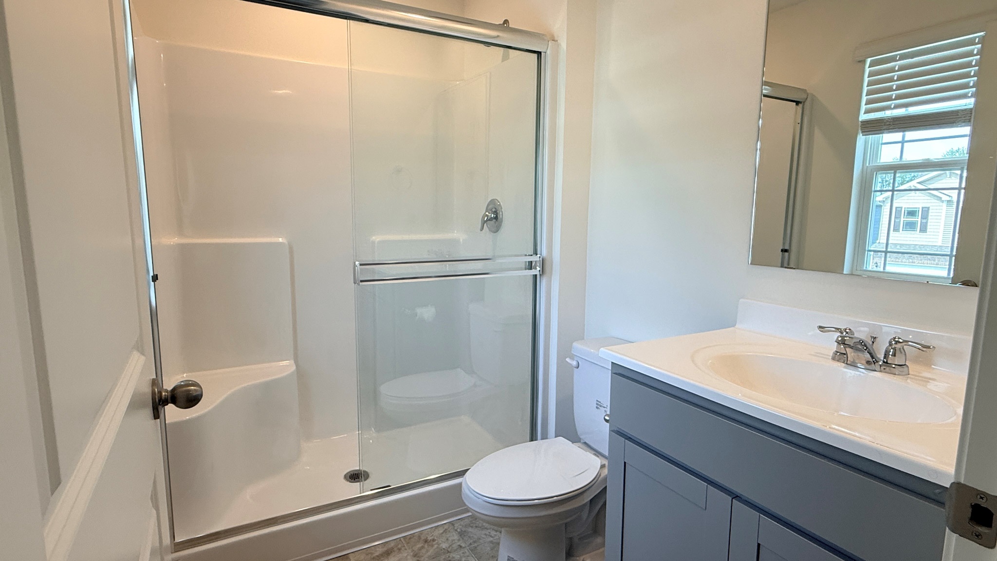 Ensuite primary bathroom with vanity, commode, and walk-in shower with sliding glass door