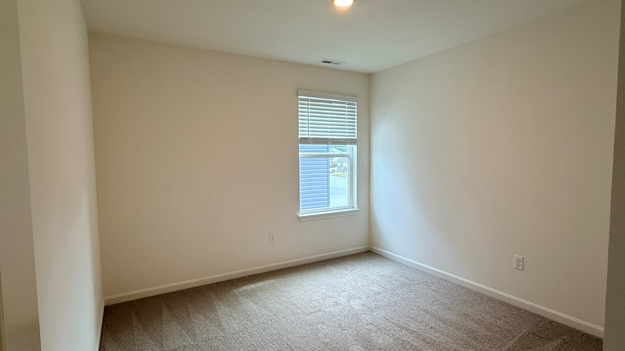 Spare bedroom with carpet and single window.