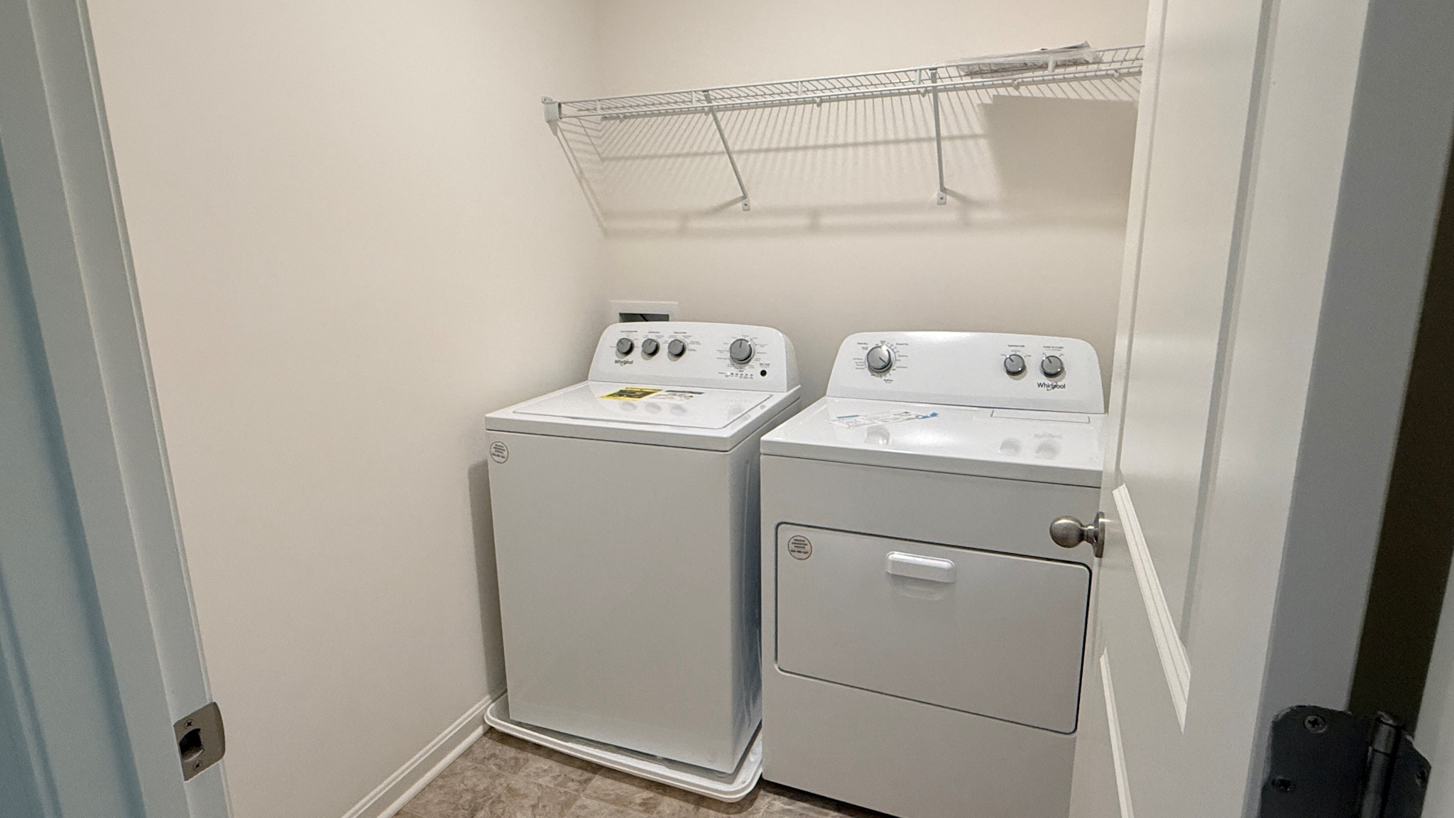 Second floor laundry room with wire shelf above the washer and dryer.