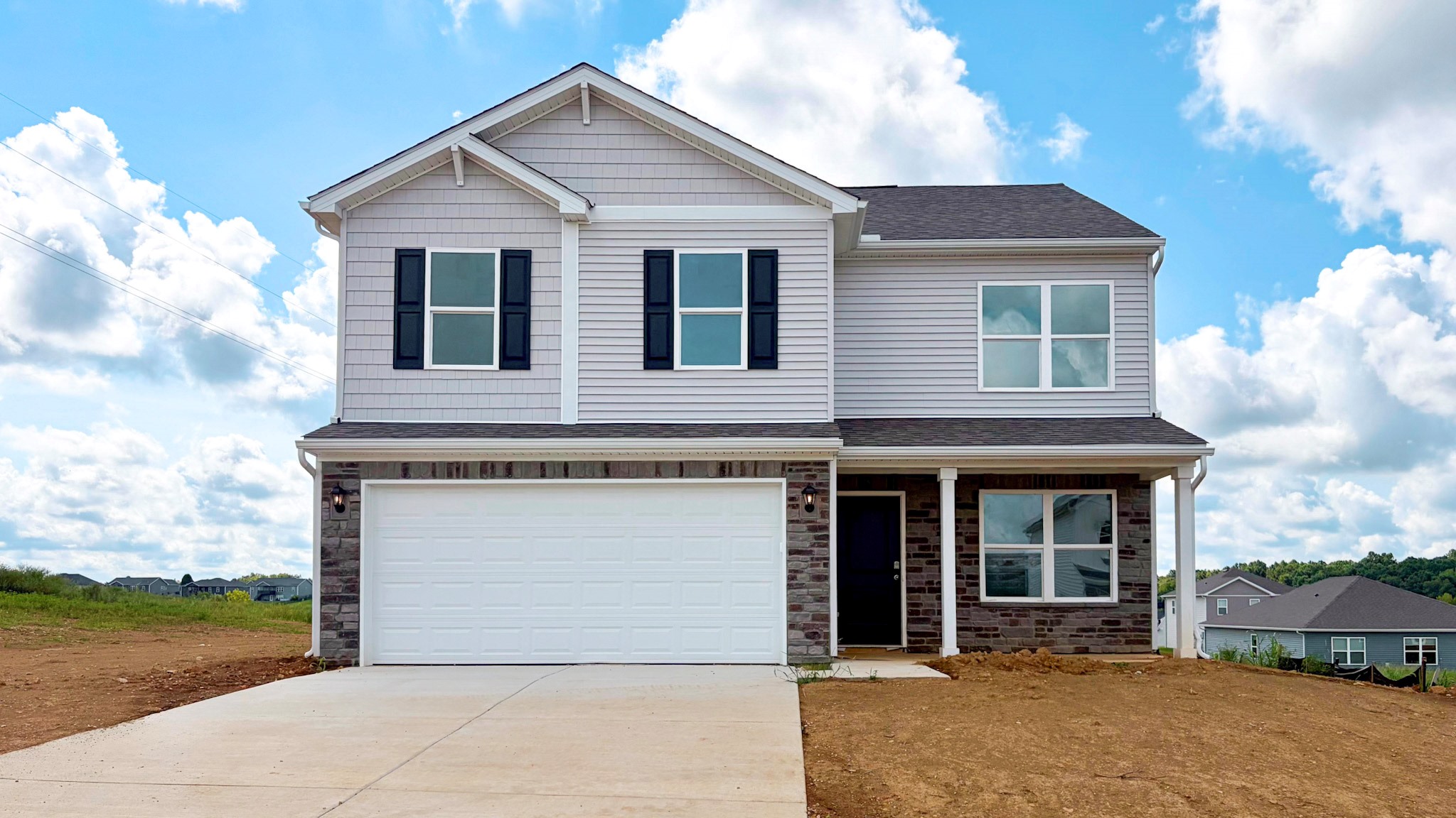 Quick move-in home with gray siding, stone accents, covered front porch, and 2-car attached garage.
