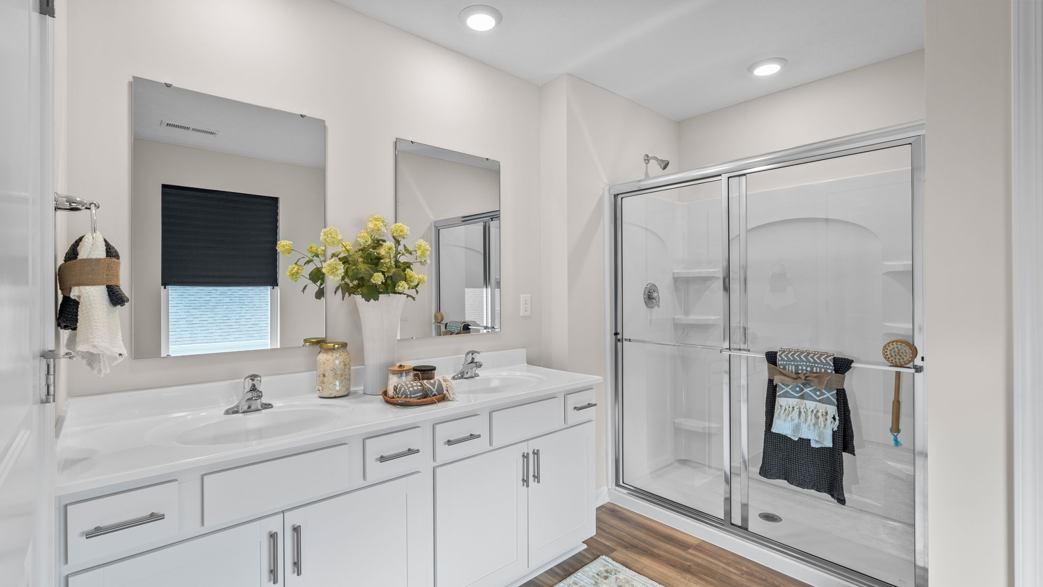Primary bathroom with double bowl vanity, walk-in shower, and LVP flooring.