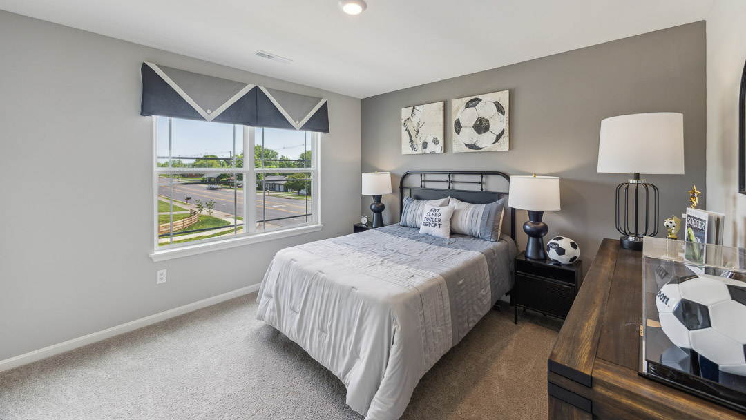 Second floor spare bedroom with double window, bed, 2 nightstands, and a dresser. Decorated in soccer theme.
