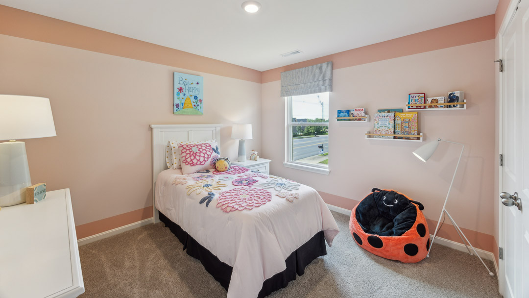 Second floor spare bedroom with pink theme. Bed, nightstand, dresser, lady bug bean bag, and single window.