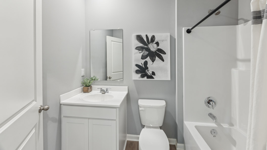 First floor full bathroom between the first floor spare bedroom and the garage entry way. Has a single bowl vanity, commode, and shower/tub combo.