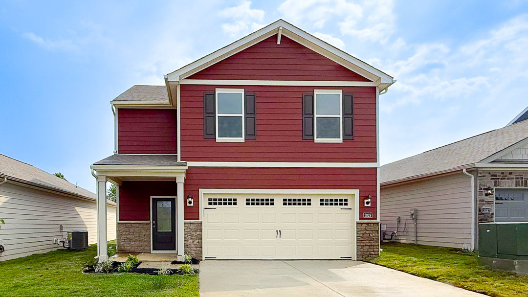 Koehler Woods Pine floor plan with red siding, a covered front porch, and a 2-car attached garage.