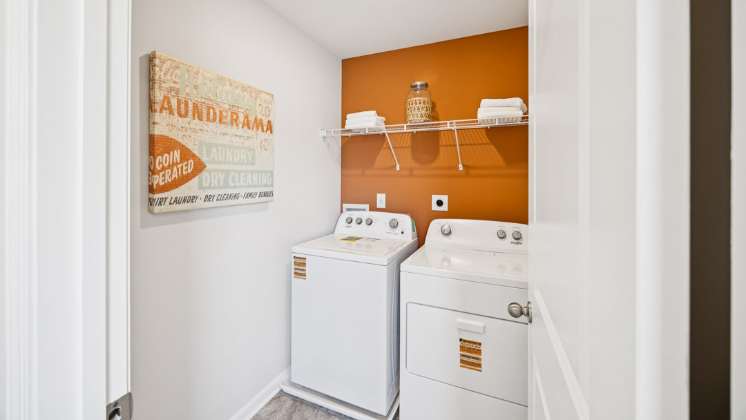 Laundry room with wire shelving above the washer and dryer.