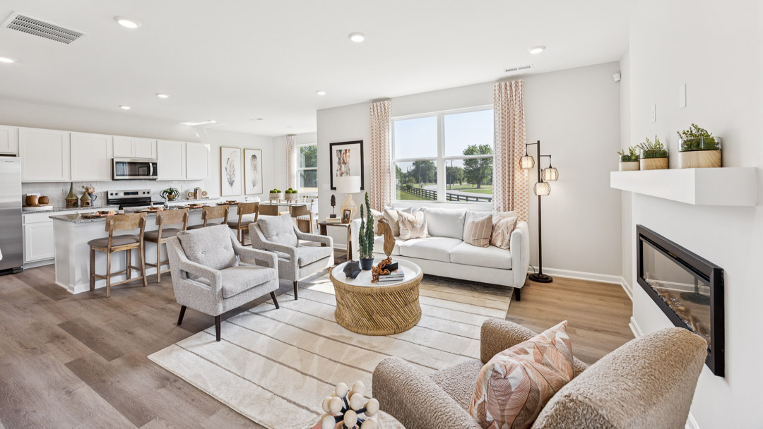 Living room with a built-in fireplace, double window overlooking the backyard, couch, 2 accent chairs, and coffee table.