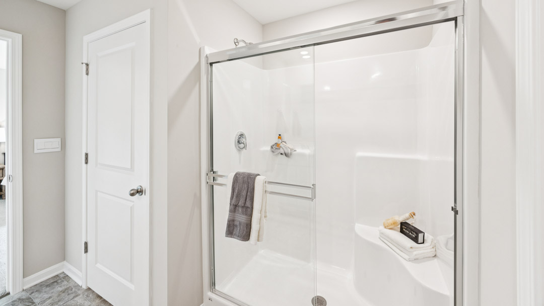 Primary bathroom walk-in shower and linen closet door.