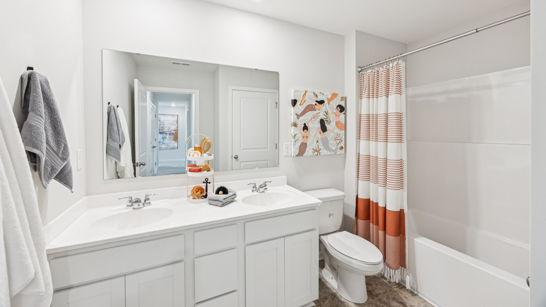 Upstairs spare bathroom with double bowl vanity, commode, and shower/tub combo.
