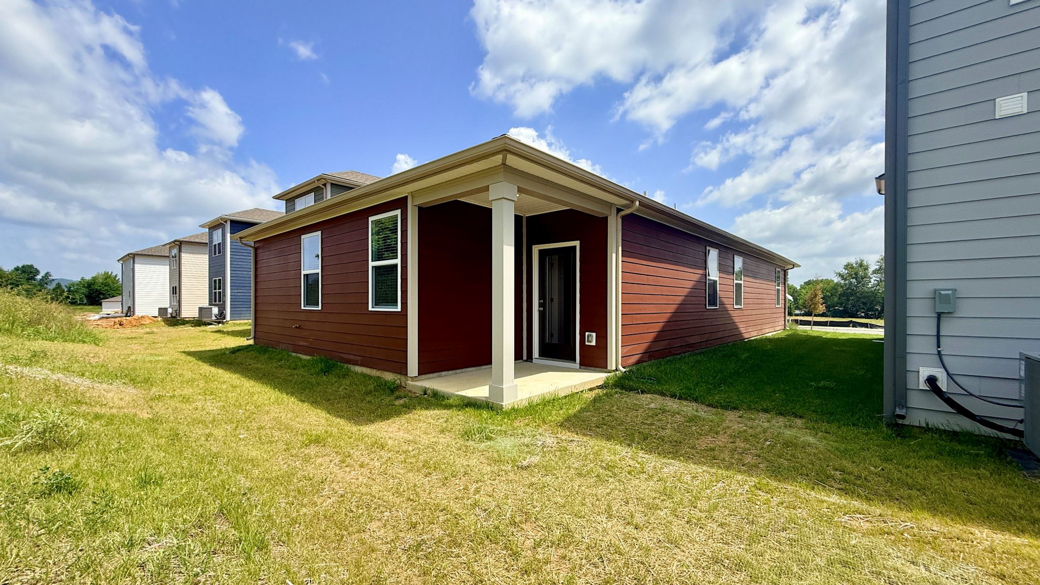 Rear of home with a covered back porch. Home has red hardie board siding.
