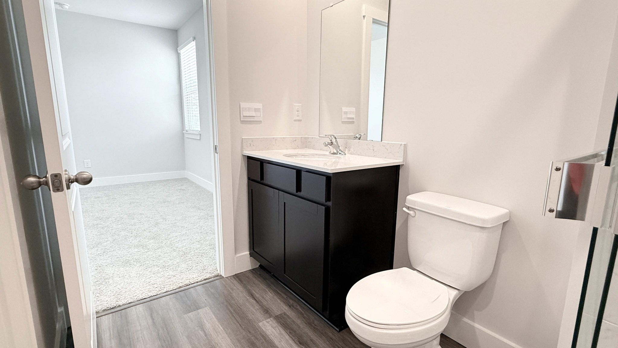 Ensuite primary bathroom with quartz vanity top and white commode.