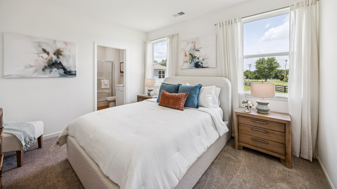 Primary bedroom with bed, 2 nightstands, 2 windows, accent chair