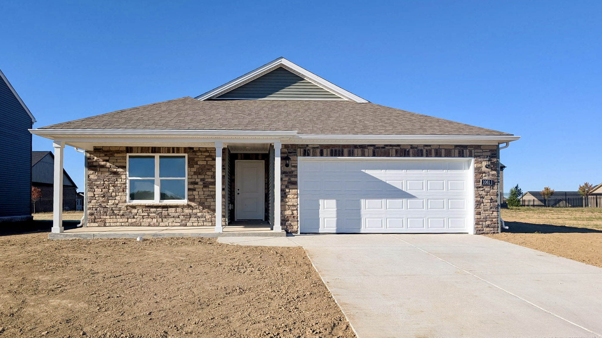 Quick move-in Harmony floor plan in Carriage Place with stone accents and green siding.