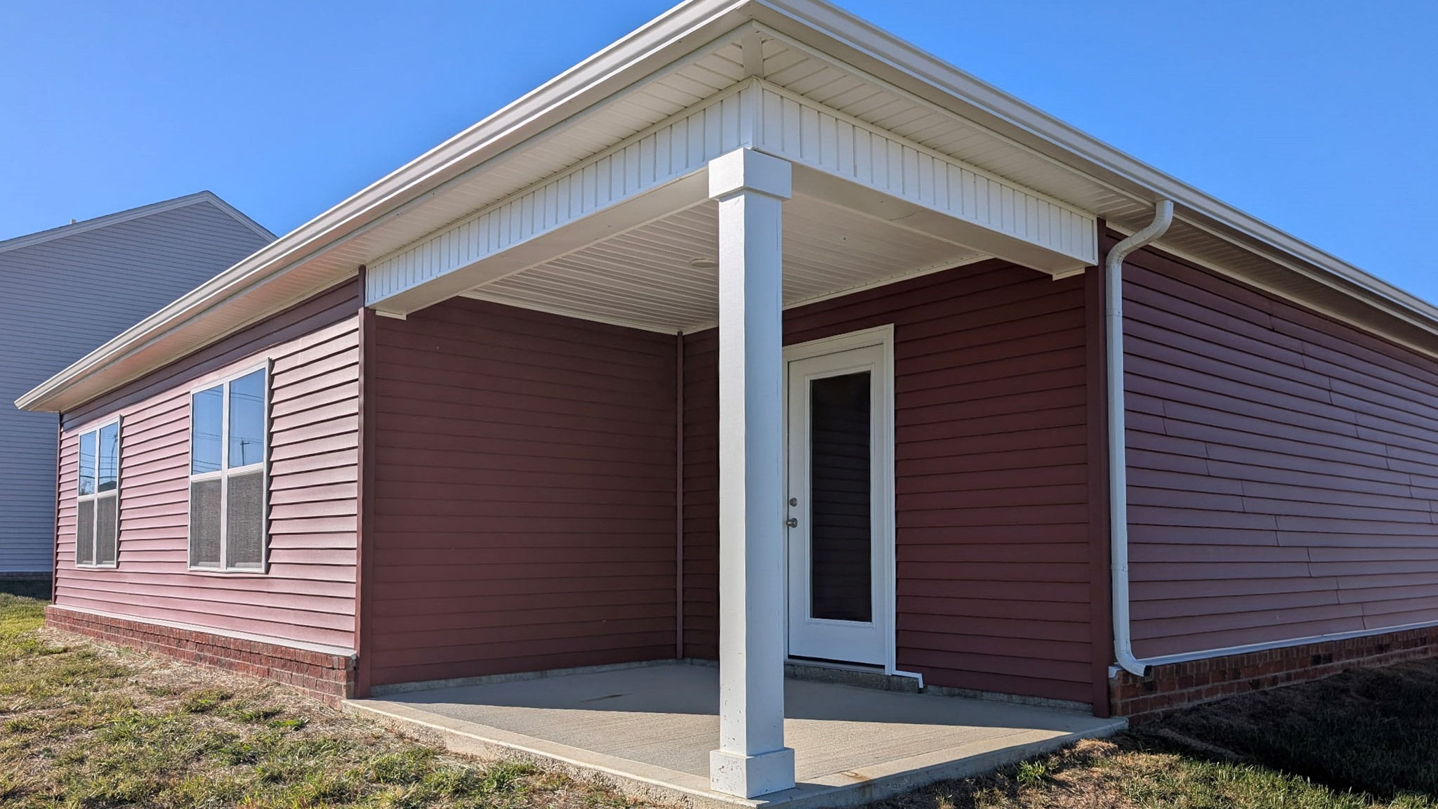 Rear of home that has red vinyl siding and a covered rear porch.
