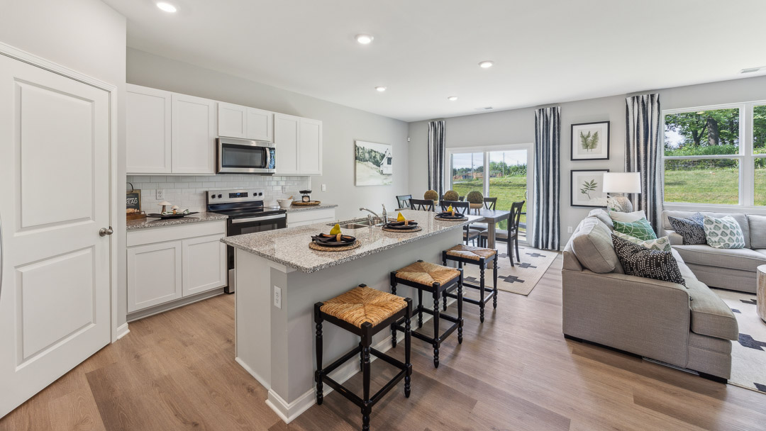 Spacious kitchen with white cabinets, quartz countertops, stainless steel appliances, and a center island.