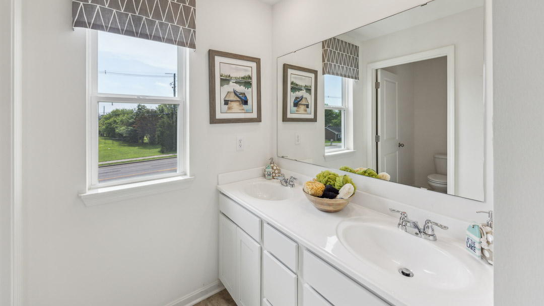 Spare bathroom with double bowl vanity and small window.