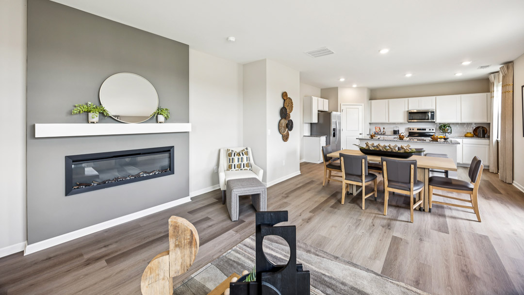 Other view of living room with built-in fireplace, dining area with table and chairs, and kitchen.