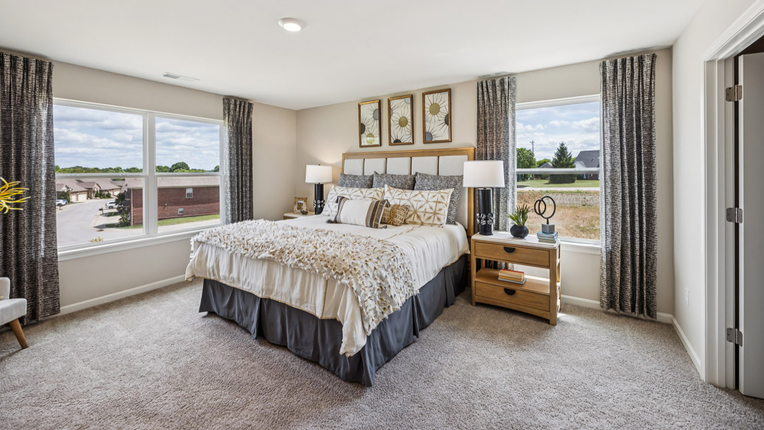Upstairs primary bedroom with king size bed, 2 nightstands, double window on one wall and a single window on the other wall.