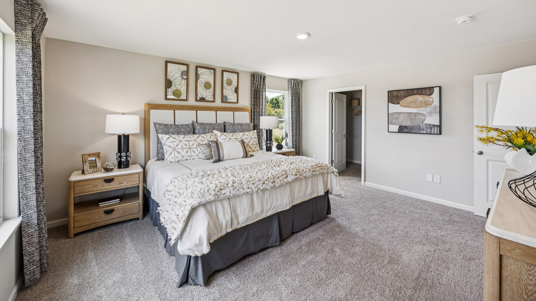 Other view of primary bedroom with king size bed, 2 nightstands, and bathroom door.