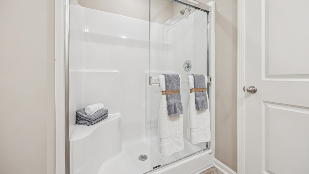 Primary bathroom walk-in shower with sliding glass door.