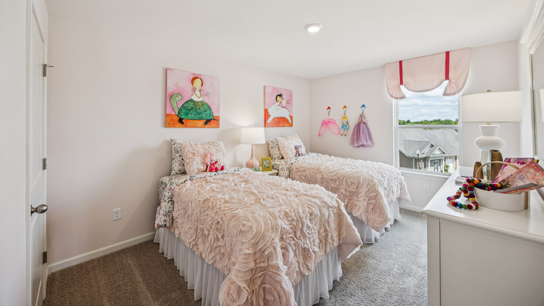 Upstairs spare bedroom with 2 twin beds, single window, and dresser. Decorated with pink theme.