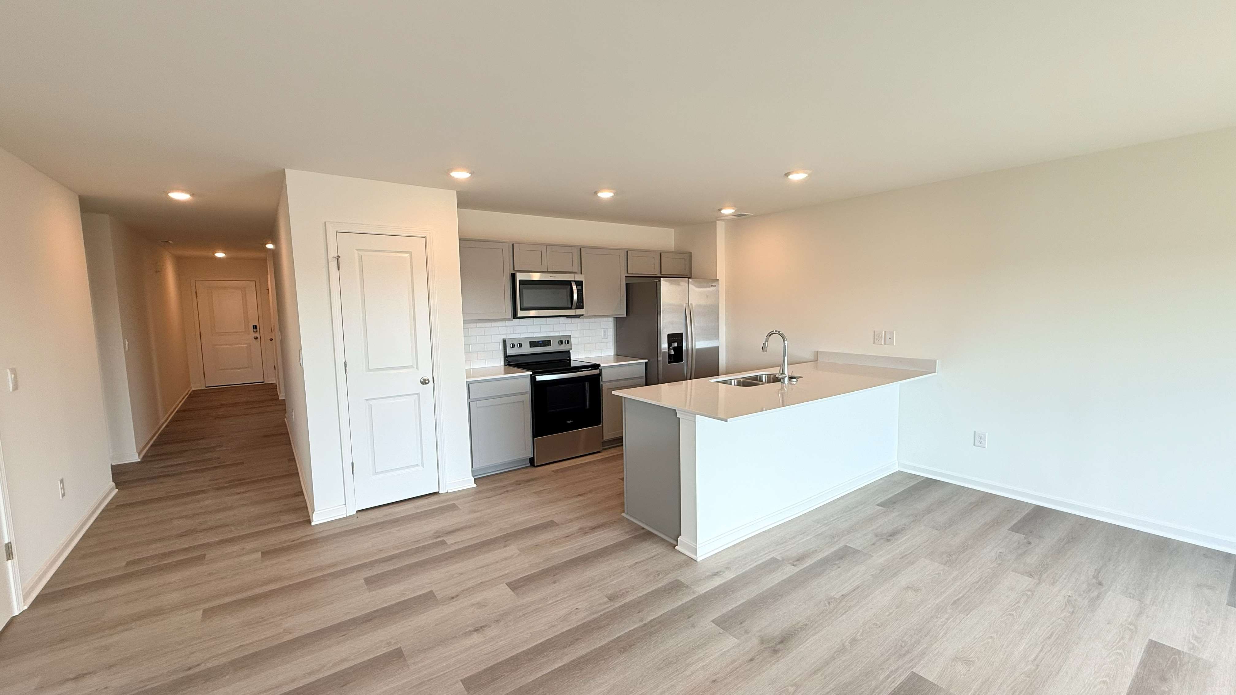 Kitchen with stone-gray cabinets, island, pantry, and stainless steel appliances.