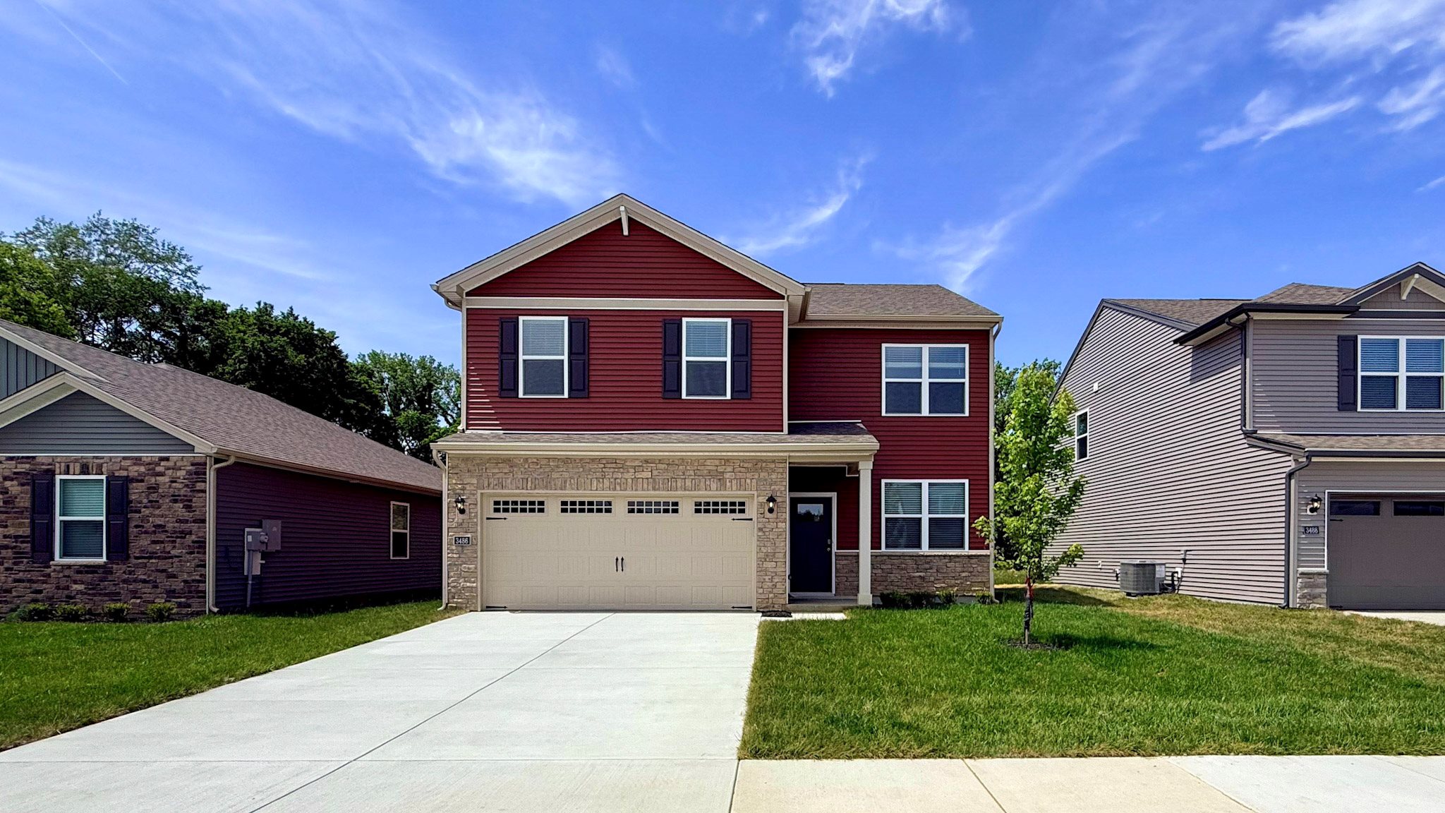 Bellamy plan with red siding, stone accents, and 2-car attached garage.
